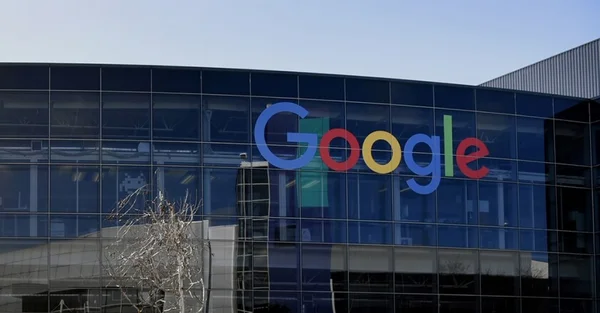 Homme souriant en chemise à carreaux sur fond beige.