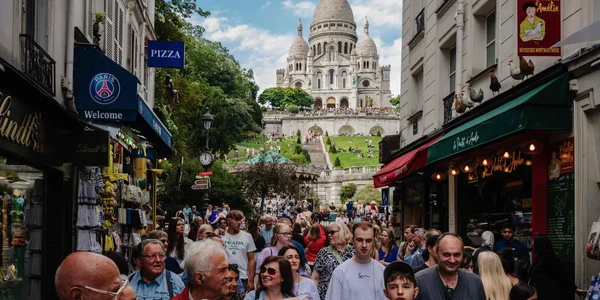 Vue d'une rue commerçante animée à Montmartre avec le Sacré-Cœur en toile de fond.