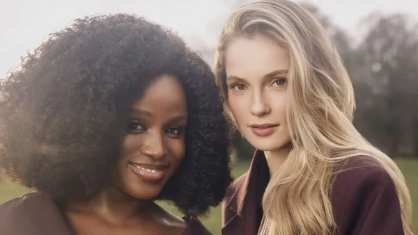 Hannah Dodd et Masali Baduza portant des blazers sombres devant une végétation floue.