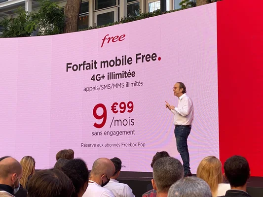 Un présentateur sur scène devant un écran affichant une offre mobile Free