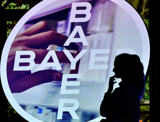 Logo de Bayer mis en avant dans un présentoir circulaire avec une main saisissant un produit.