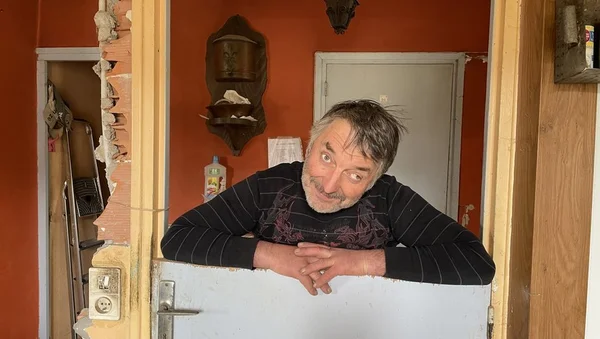 Didier l'Aveyronnais dans son intérieur, appuyé sur une porte blanche.
