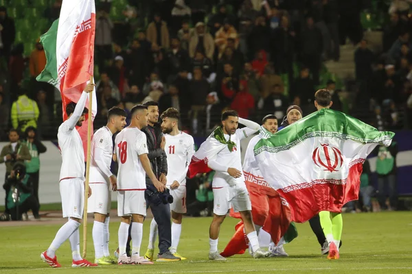 Célébration des joueurs iraniens drapés dans le drapeau national après une victoire en Coupe du monde.