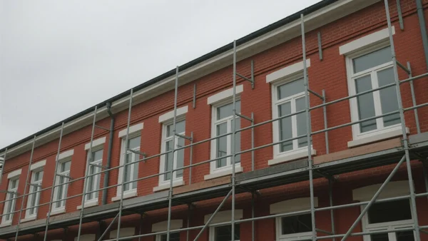 Façade en brique rouge typique d'un immeuble lillois en cours de rénovation énergétique, échafaudage installé, fenêtres neuves en place, lumière grise du Nord