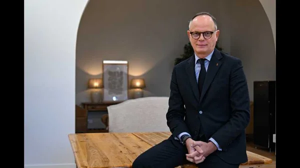 Édouard Philippe assis, mains croisées, dans une pièce décorée.