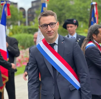 Antoine Léaument en costume avec écharpe tricolore lors d'une apparition publique.