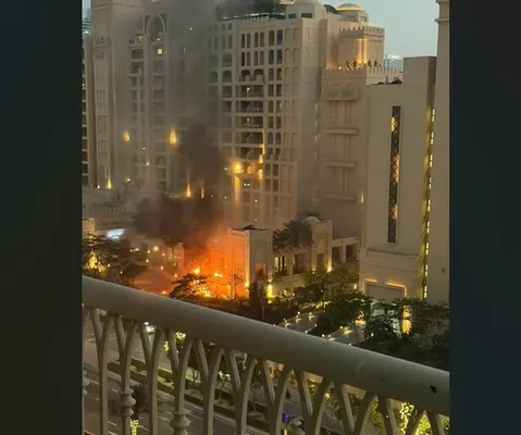 Un bâtiment en flammes dégageant une épaisse fumée noire dans une rue de l'île The Palm à Dubaï.