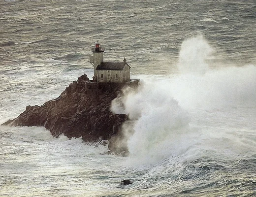 Une puissante vague frappe le rocher où se dresse le phare du Tévennec.