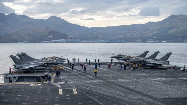 Chasseurs militaires et équipage sur le pont d'un porte-avions en mer.