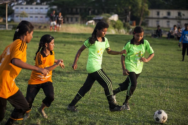 Des jeunes filles s'affrontent lors d'un match de football sur un terrain d'herbe.