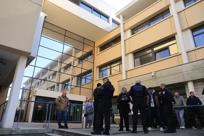 Policiers et civils réunis devant un bâtiment officiel moderne.