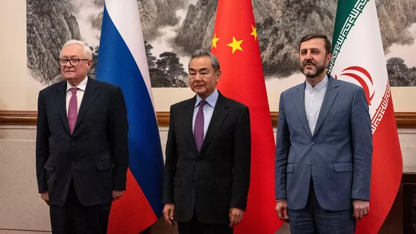 Trois diplomates posent devant les drapeaux de la Russie, de la Chine et de l'Iran lors d'une rencontre officielle.