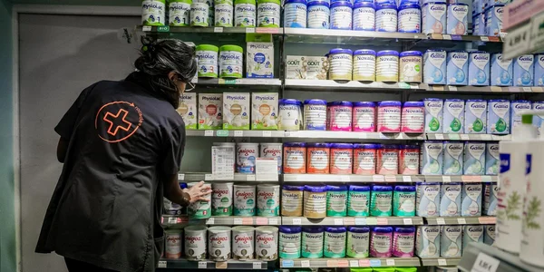 Une personne en uniforme noir range des produits sur une étagère de magasin.