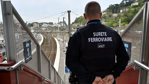 Un agent de la Sûreté ferroviaire SNCF surveille une station depuis un escalier.