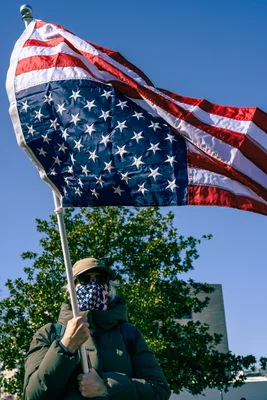 Un manifestant lors du rassemblement No Kings Day du mouvement 50501 au Capitole, tenant un drapeau américain inversé sous un ciel dégagé.