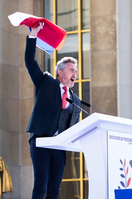 Stéphane Ravier lors d'un discours au Trocadéro, levant un drapeau français.