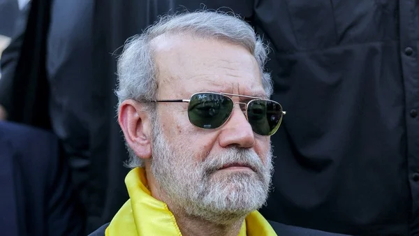 Gros plan sur Ali Larijani portant des lunettes de soleil et un col jaune.