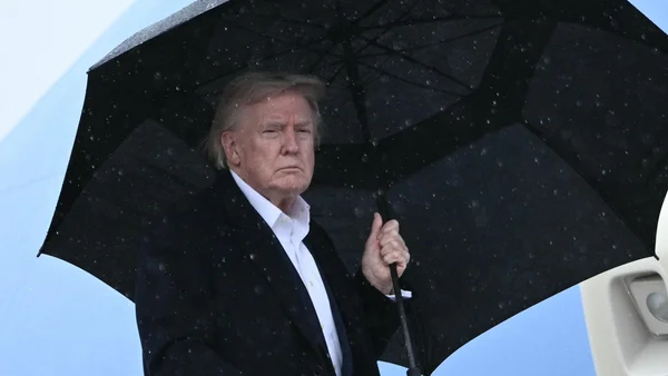 Donald Trump sous la neige avec un parapluie noir.