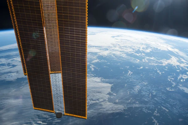 Vue depuis l'espace montrant la courbe lumineuse de l'atmosphère terrestre avec une constellation de satellites passant devant, fond étoilé profond