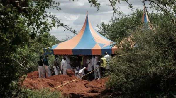 Des équipes médico-légales exhumant des corps sur un site de la forêt de Shakahola sous une tente d'investigation.