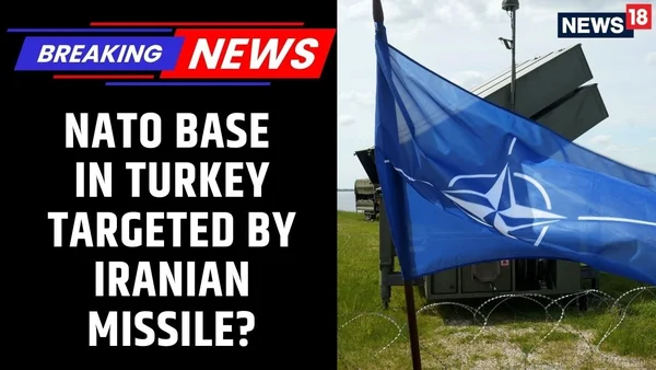 Drapeau de l'OTAN flottant devant une structure militaire clôturée.