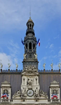 Le beffroi ornementé de l'Hôtel de Ville de Paris, arborant les drapeaux français et européen.
