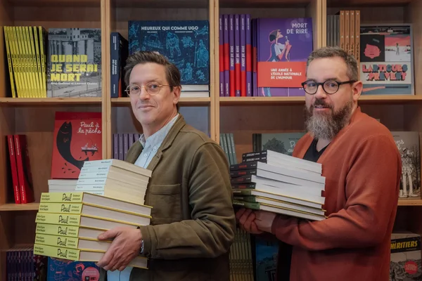 Dirigeants des éditions La Pastèque et Bayard Canada posant devant une rayonnure de livres.