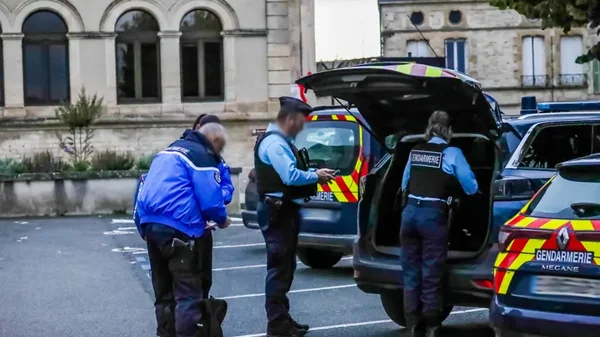 Des gendarmes rassemblés autour d'une voiture de police lors d'une intervention.