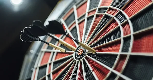 Trois flèches plantées près du centre d'une cible de fléchettes lors du tournoi entre créateurs