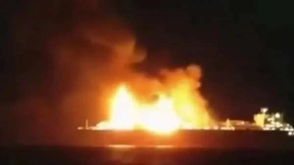 Un violent incendie avec des flammes oranges et de la fumée s'échappe d'un navire la nuit.