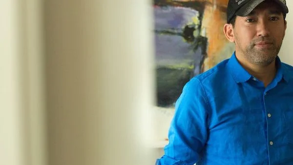 Shinji Mikami en chemise bleue et casquette de baseball.