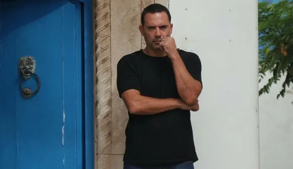 Dhafer L'Abidine, réalisateur de Sophia, debout devant une porte bleue à heurtoir en lion.