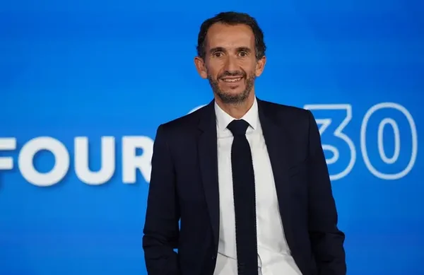 Alexandre Bompard posant devant un fond bleu officiel