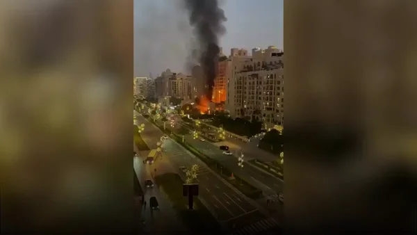 Incendie nocturne dans un bâtiment de l'île The Palm avec des flammes visibles et de la fumée.