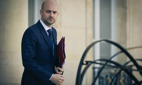 Jean-Noël Barrot en costume tenant un dossier lors d'une déclaration publique.