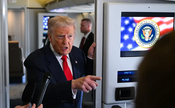 Donald Trump gesticulant devant le sceau présidentiel à bord d'un avion.