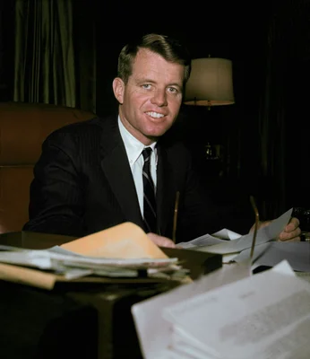 Robert Kennedy travaillant à son bureau de procureur général, entouré de dossiers.