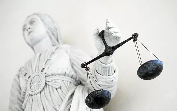 Détail d'une statue représentant la justice et ses balances, évoquant le cadre légal européen.