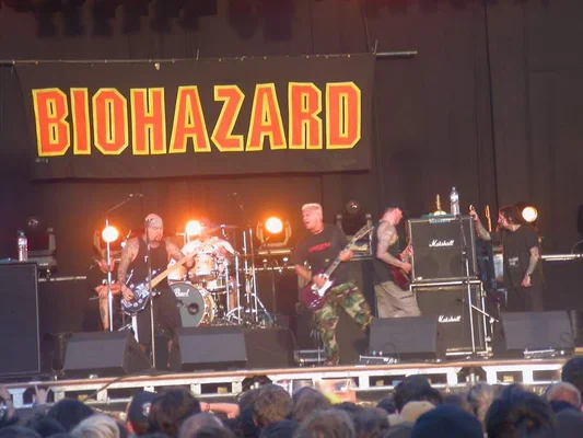 Vue aérienne de nuit du festival montrant une scène circulaire entourée d'une foule immense illuminée de rouge et bleu.