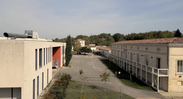 Le collège Rambaud en Gironde, mêlant architecture moderne et bâtiment traditionnel en pierre sous un ciel dégagé.