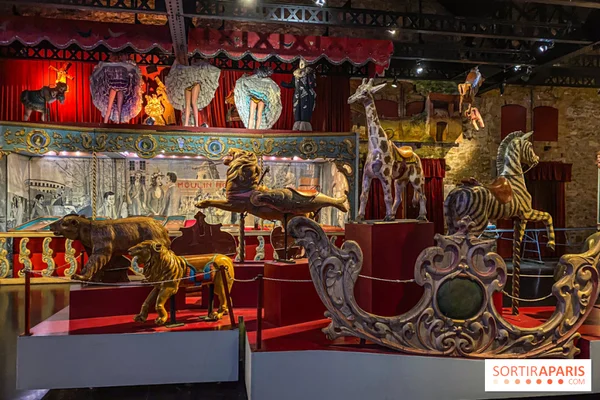 Détail d'un carrousel ancien avec ses calèches dorées et ses animaux sculptés, baigné d'une lumière chaleureuse.