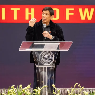 Homme en veste noire encerclé par une foule prenant des photos.