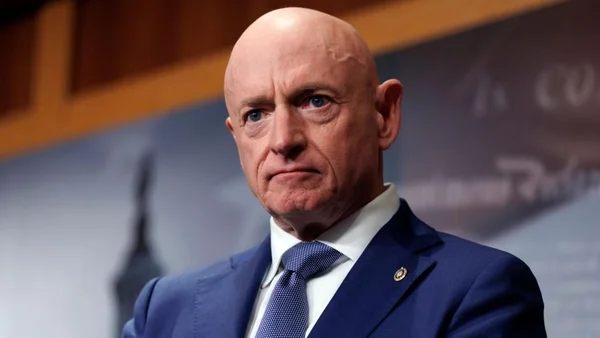 Le sénateur Mark Kelly en costume devant un fond en bois flou.