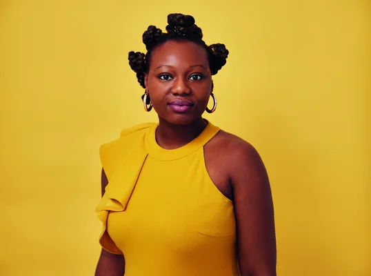 Mirrianne Mahn, auteure d'« Issa » chez Stock, en haut jaune et rouge à lèvres violet devant un fond jaune.