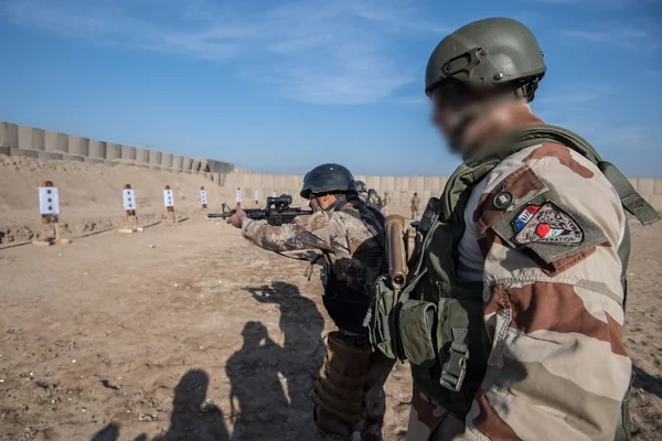 Soldats français s'entraînant au tir sur un stand extérieur, avec un mur en béton en arrière-plan.