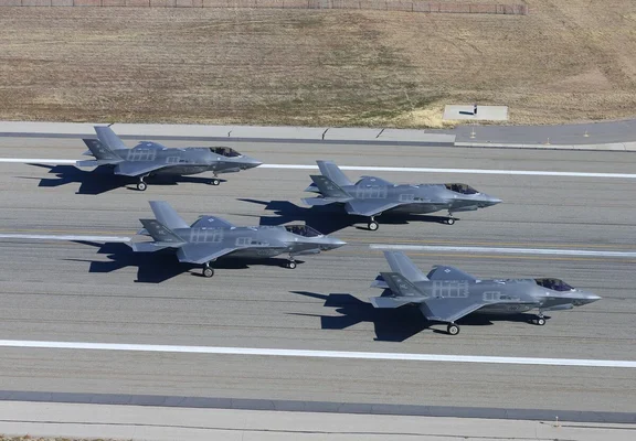 Quatre avions de chasse F-35 positionnés sur une piste goudronnée.