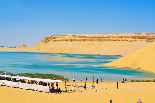 Un lac turquoise scintillant au cœur des dunes de sable de l'oasis du Fayoum.