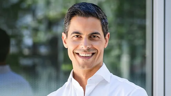 Rob Jetten en chemise blanche souriant devant un paysage flou.