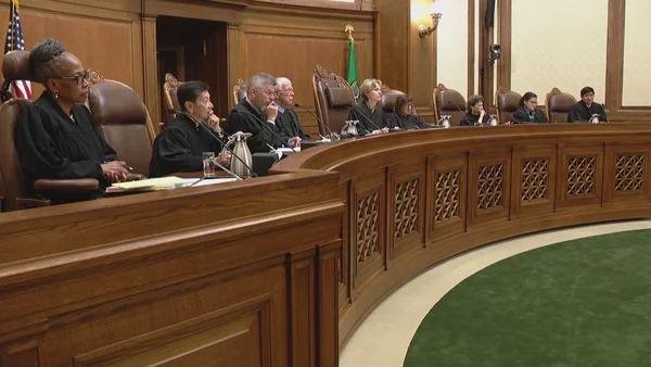 Un groupe de juges en robes noires assis à un banc en bois dans une salle d'audience.