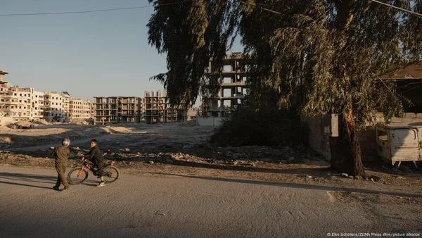 Enfants jouant dans un quartier aux bâtiments inachevés, illustrant le quotidien en Syrie.